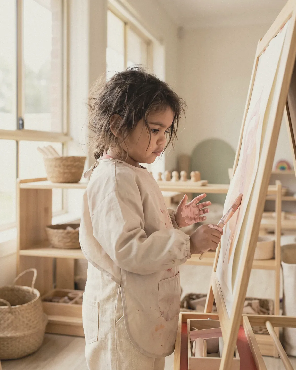 A girl painting at a wooden easel