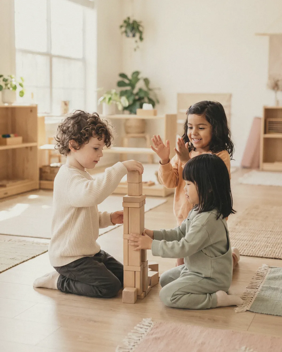 Three children building a tall tower of wooden blocks together